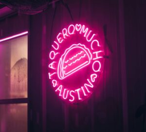Neon pink sign in Austin reading “Taquero Mucho” with a glowing taco illustration, creating a playful and romantic ambiance — perfect for a fun date-night vibe.