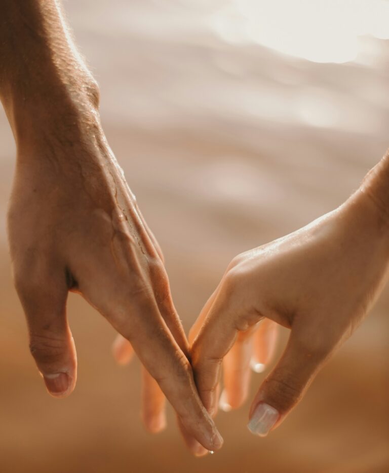 Close-up of two hands forming a heart shape with their fingers in warm sunlight, symbolizing mutual consent and connection.
