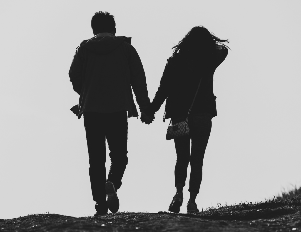 Couple holding hands while walking together, representing healthy relationships, repair, and coming back to each other after difficult moments.